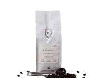 Wildflower Coffee Company presents their Rainforest Espresso Blend in a white bag with a scoop and scattered beans.

