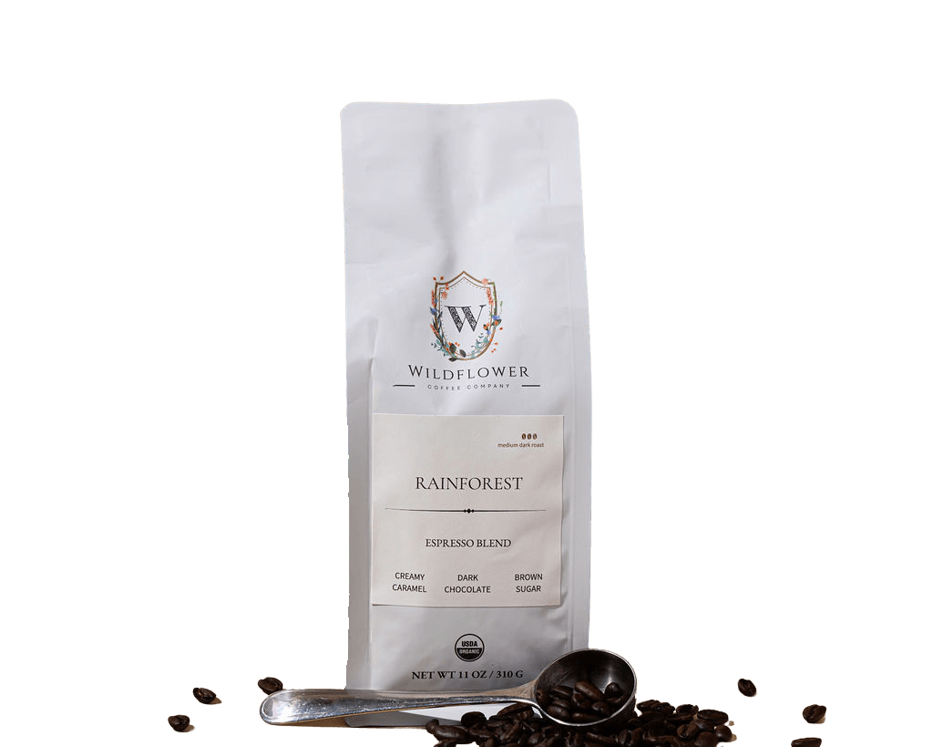Wildflower Coffee Company presents their Rainforest Espresso Blend in a white bag with a scoop and scattered beans.
