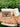 Three bars of Rowe Naturals tallow soap rest on a wood slice against a green leafy background.
