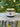 Rowe Naturals grass-fed whipped tallow sits on a textured tree stump against a blurred green background.
