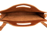 A brown leather tote bag sits open, revealing its spacious, unlined interior.
