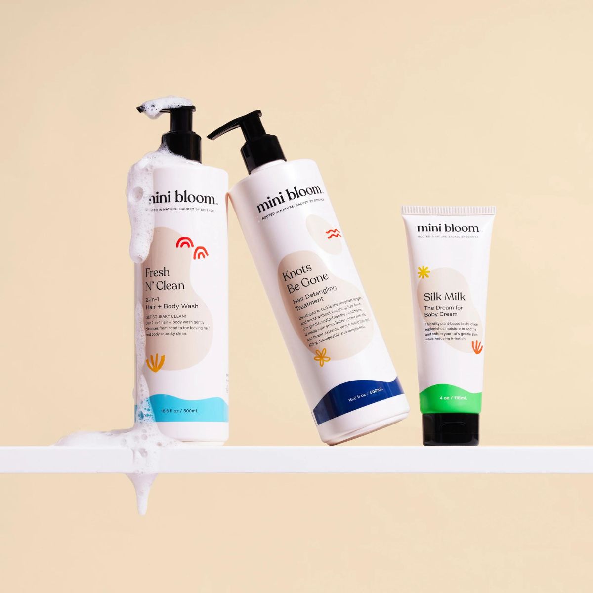 Mini Bloom skincare products, including hair and body wash, detangling treatment, and baby cream, sit on a shelf.
