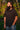 Bearded man with long hair and black t-shirt gazes thoughtfully into the distance outdoors.
