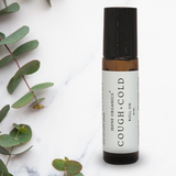 Irene Organics Cough and Cold roll-on remedy sits alongside fresh eucalyptus leaves.
