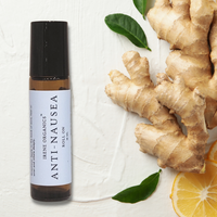 Irene Organics Anti-Nausea Roll-On rests near fresh ginger root, lemon slices, and green leaves.
