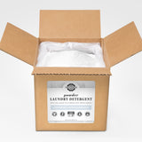 Open box reveals a bag filled with Rustic Strength unscented, hypoallergenic powder laundry detergent, detoxing laundry with earth-derived minerals.