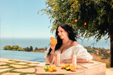 Woman enjoys a refreshing Gorgie cocktail by the infinity pool overlooking the ocean.
