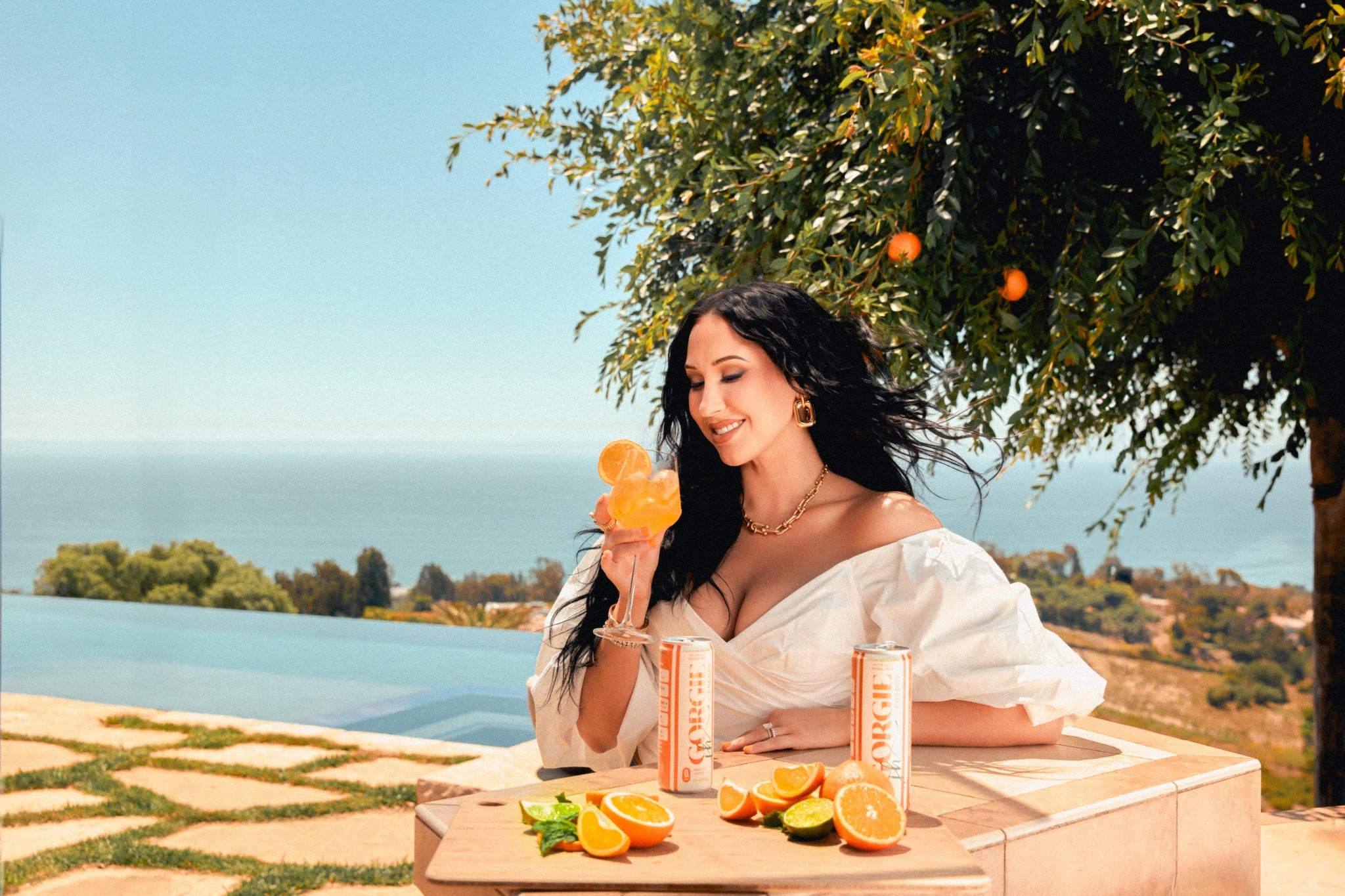 Woman enjoys a refreshing Gorgie cocktail by the infinity pool overlooking the ocean.
