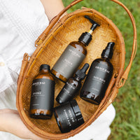 Basket with skincare products labeled 'Grace + Rae' held by a person outdoors.
