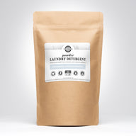 A kraft paper bag presents Rustic Strength powder laundry detergent, advertising unscented, hypoallergenic, and earth-derived minerals.
