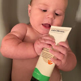 Baby chews on a tube of Mini Bloom Dream Baby Cream.

