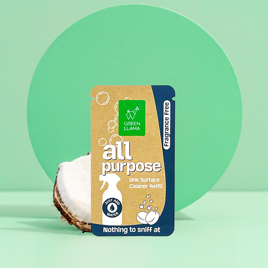 Green Llama presents its all-purpose, fragrance-free cleaner refill packet next to a halved coconut.
