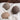 Three wool dryer balls rest on a soft, white terry towel against a dark wooden background.
