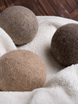 Three wool dryer balls sit nestled on a fluffy white towel.