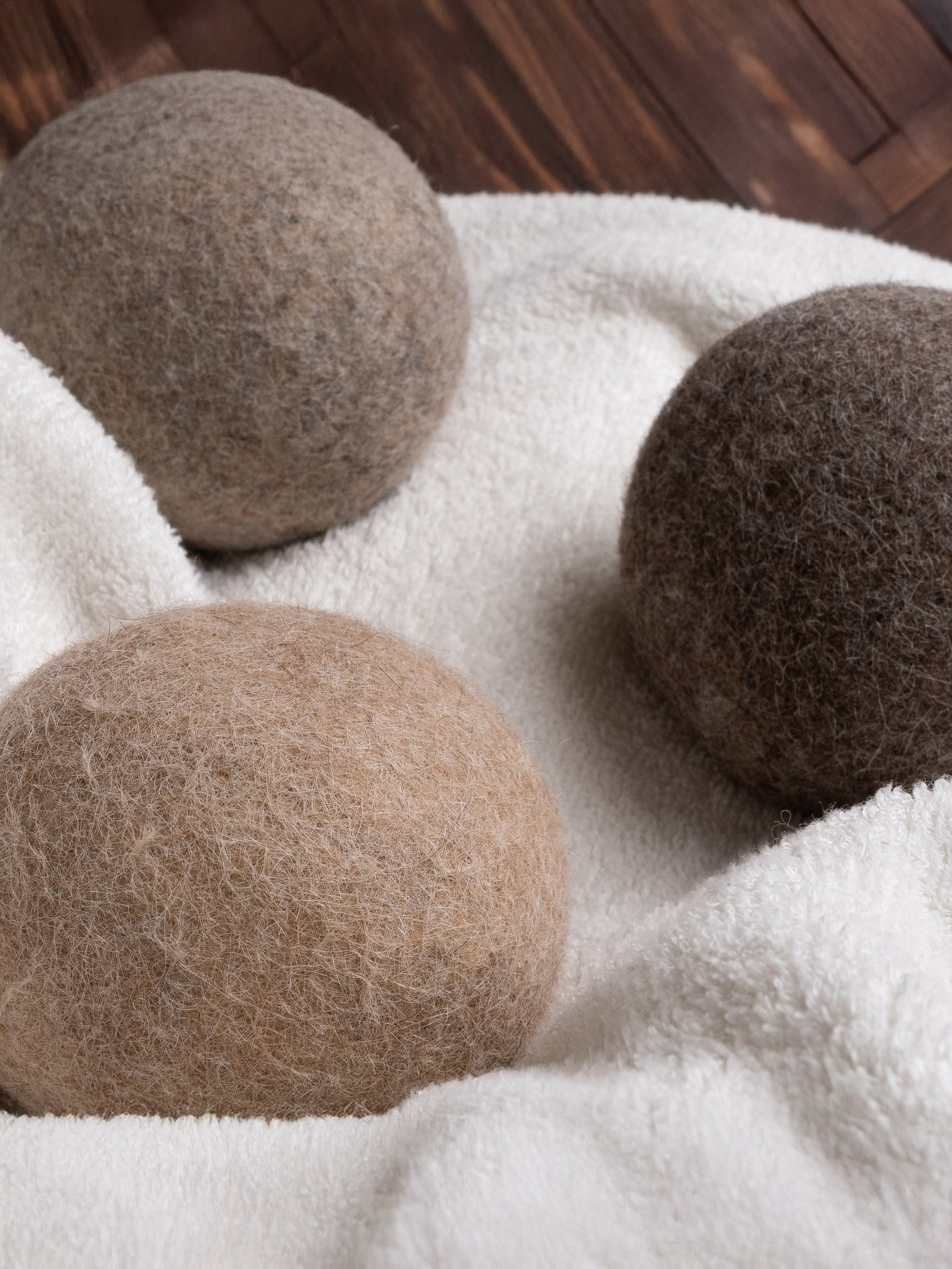 Three wool dryer balls sit nestled on a fluffy white towel.