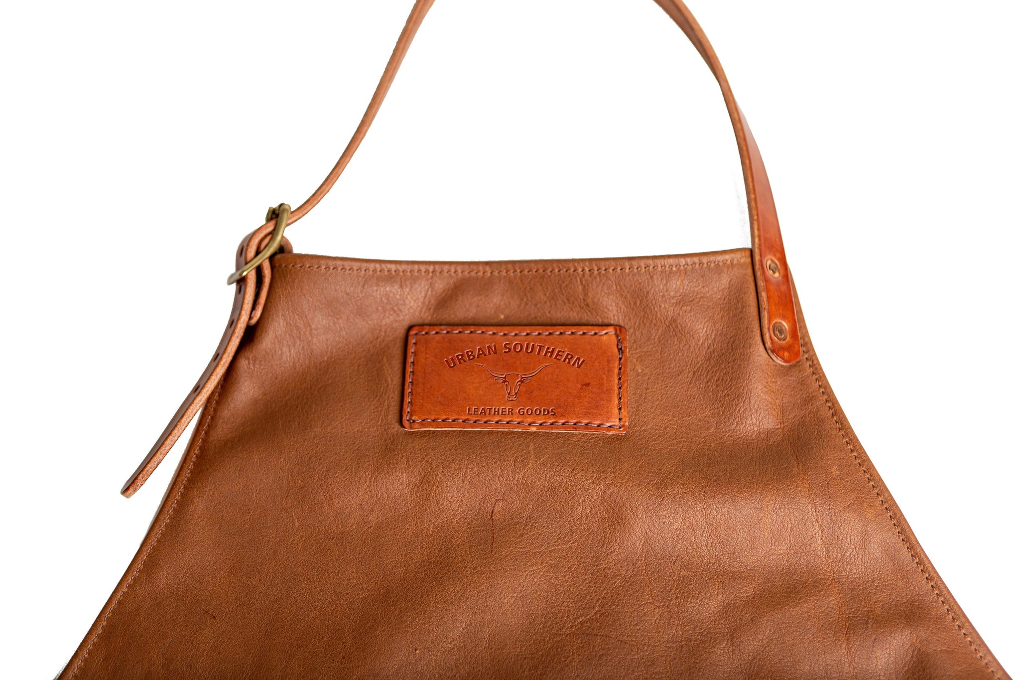 Close-up shows a stylish "Urban Southern" leather apron featuring adjustable straps and a stitched logo patch.
