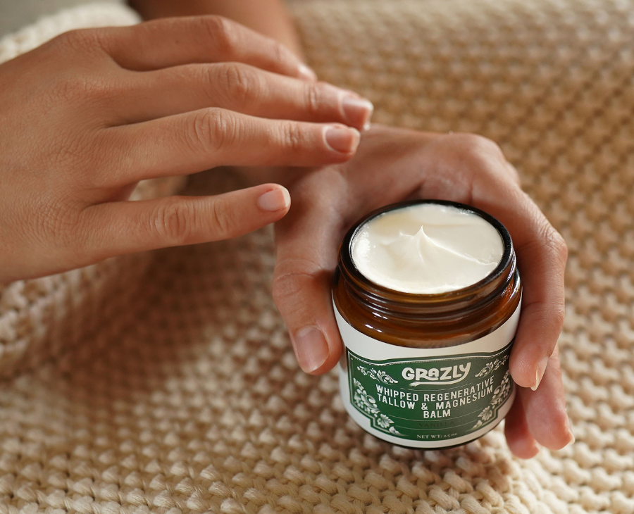 Person holding a jar of Grazly balm on a textured surface