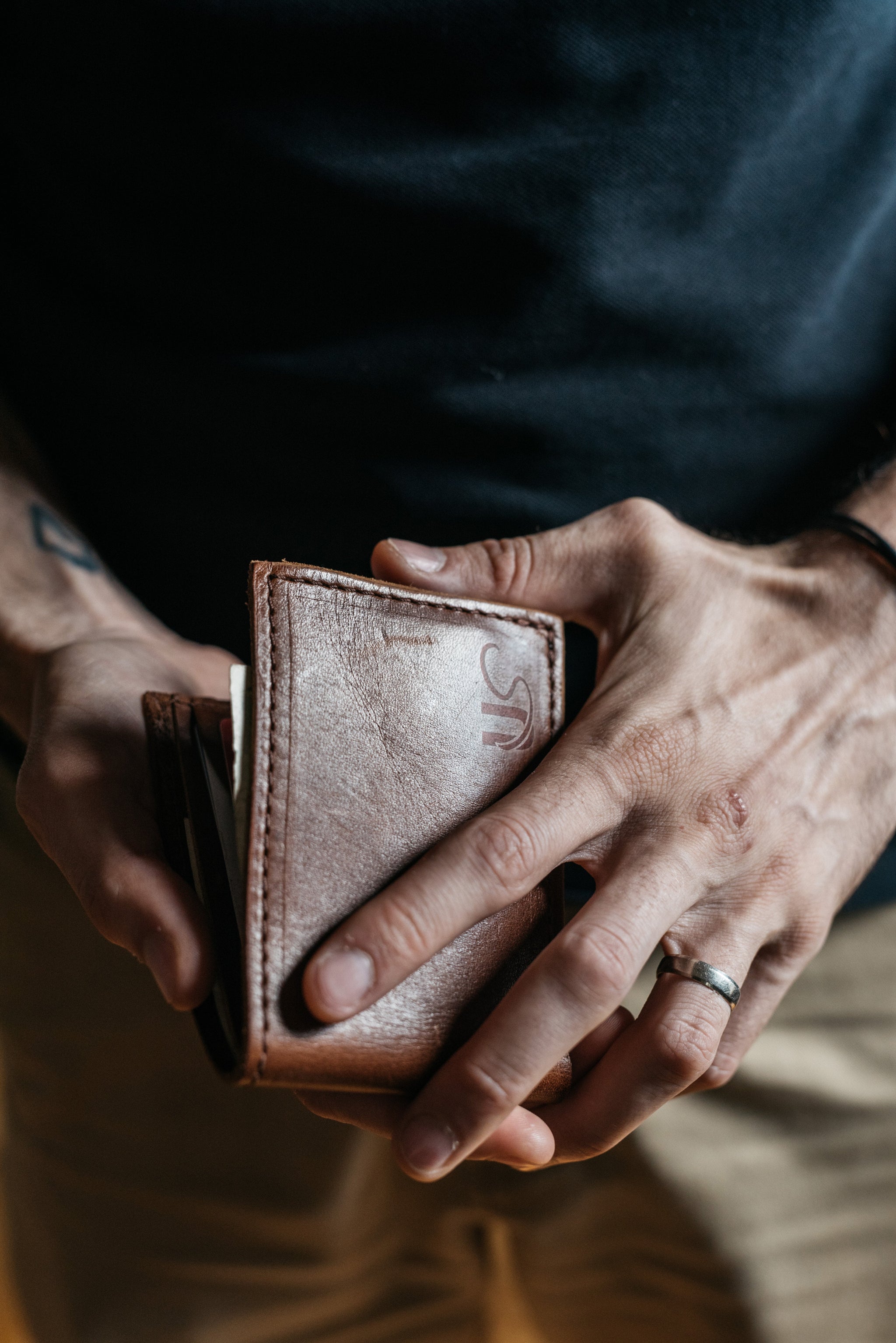 Man holds a personalized brown leather wallet in his hands.
