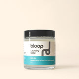 Bloop laundry soap in a glass jar with a "Salt Air" scent label, featuring mandarin orange, sea water, clary sage, and driftwood notes.