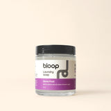 Bloop laundry soap sits in a clear jar, advertising a stone fruit scent of apricot, peach, and plum.
