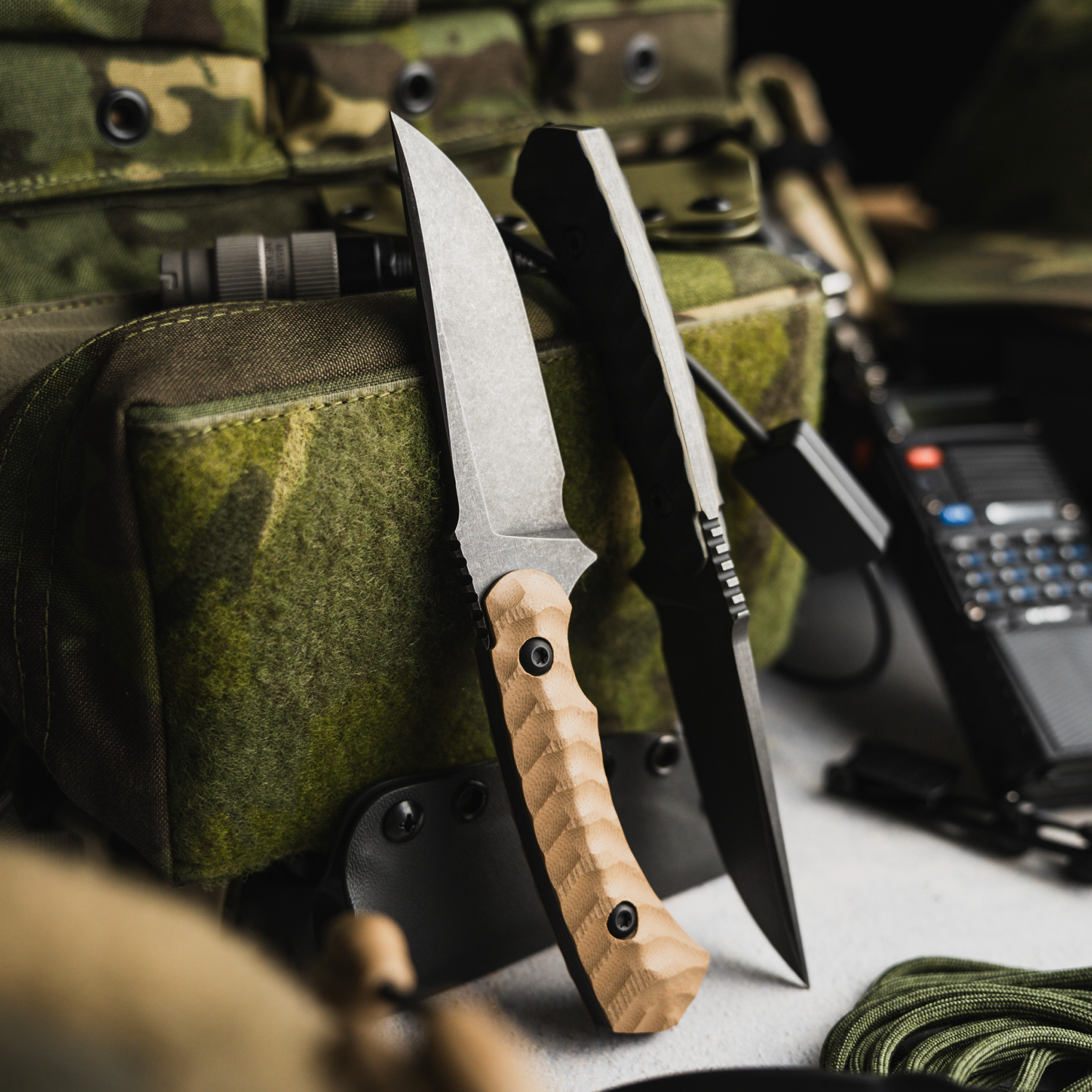 Two knives with wooden handle and metal blade on a camouflage background