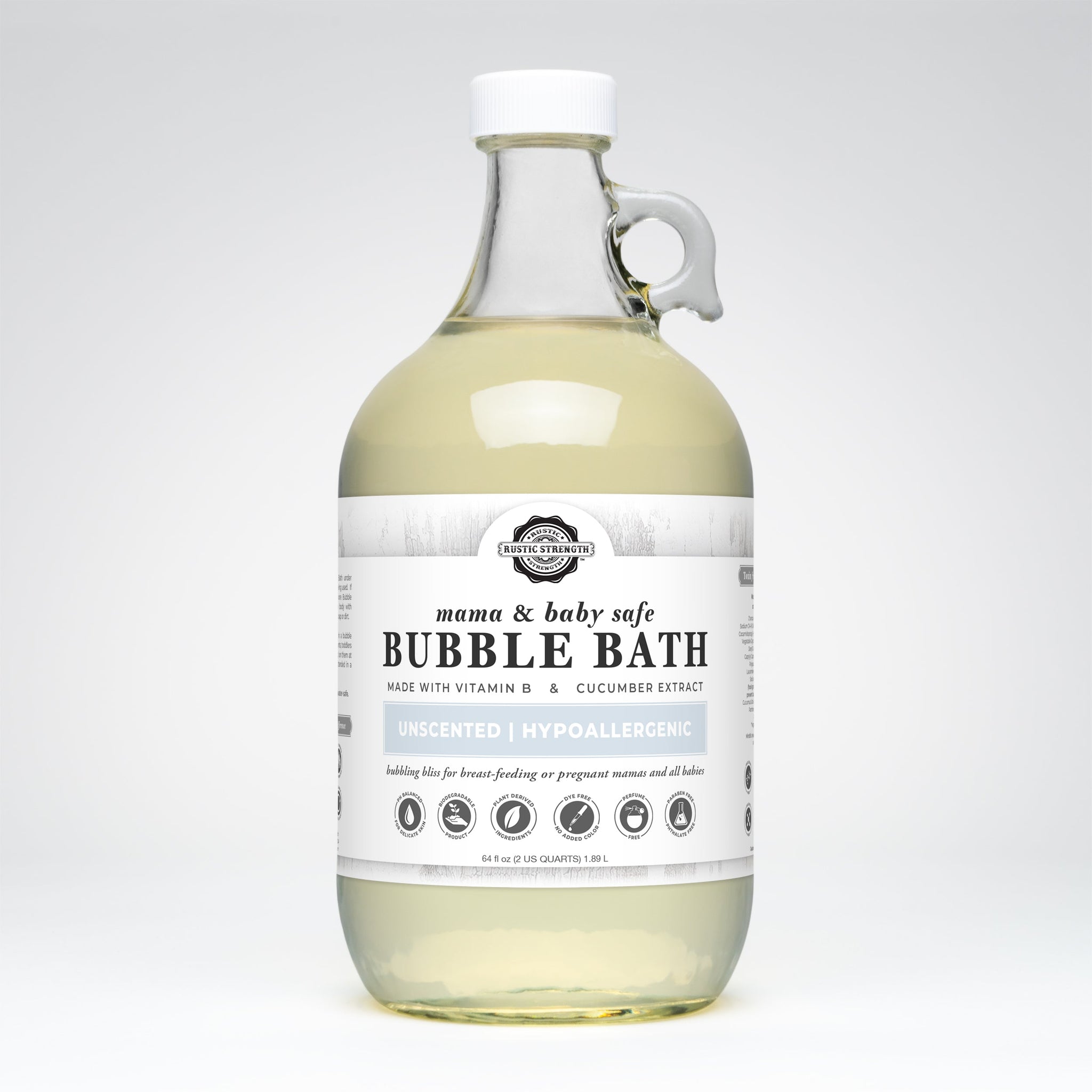 A clear glass jug displays Rustic Strength mama & baby safe unscented bubble bath, highlighting its vitamin B and cucumber extract ingredients.
