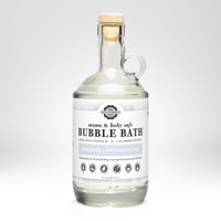 Rustic Strength presents its mama and baby safe, unscented, hypoallergenic bubble bath in a clear glass bottle with a cork stopper.
