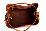 Top-down view showcases the interior of a stylish brown leather bucket bag featuring a zippered pocket.
