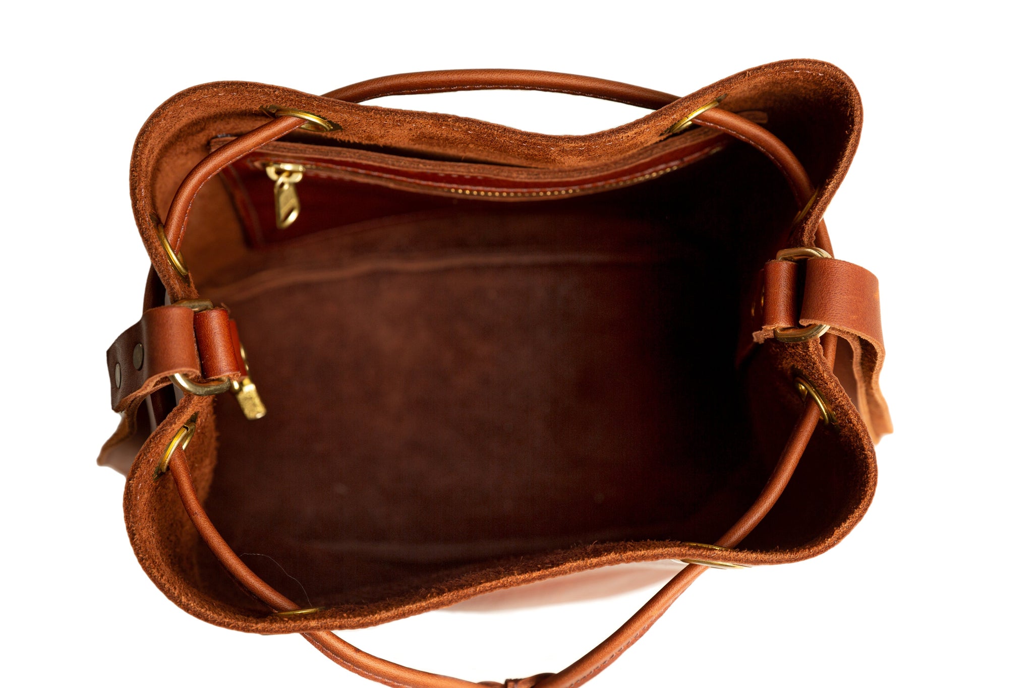 Top-down view showcases the interior of a stylish brown leather bucket bag featuring a zippered pocket.
