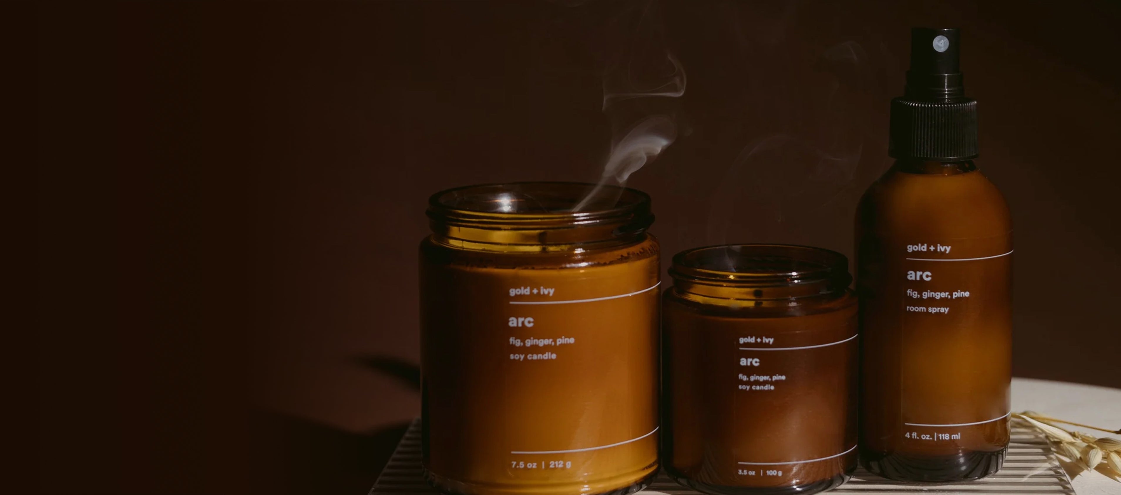 Two amber candles and one amber room spray sitting on a table