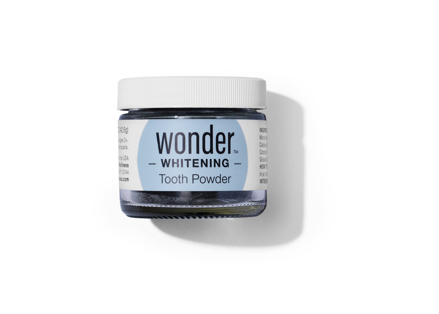 A jar of Wonder Whitening Tooth Powder sits on a white surface.
