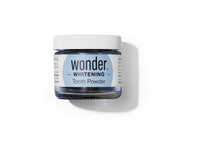 A jar of Wonder Whitening Tooth Powder sits on a white surface.
