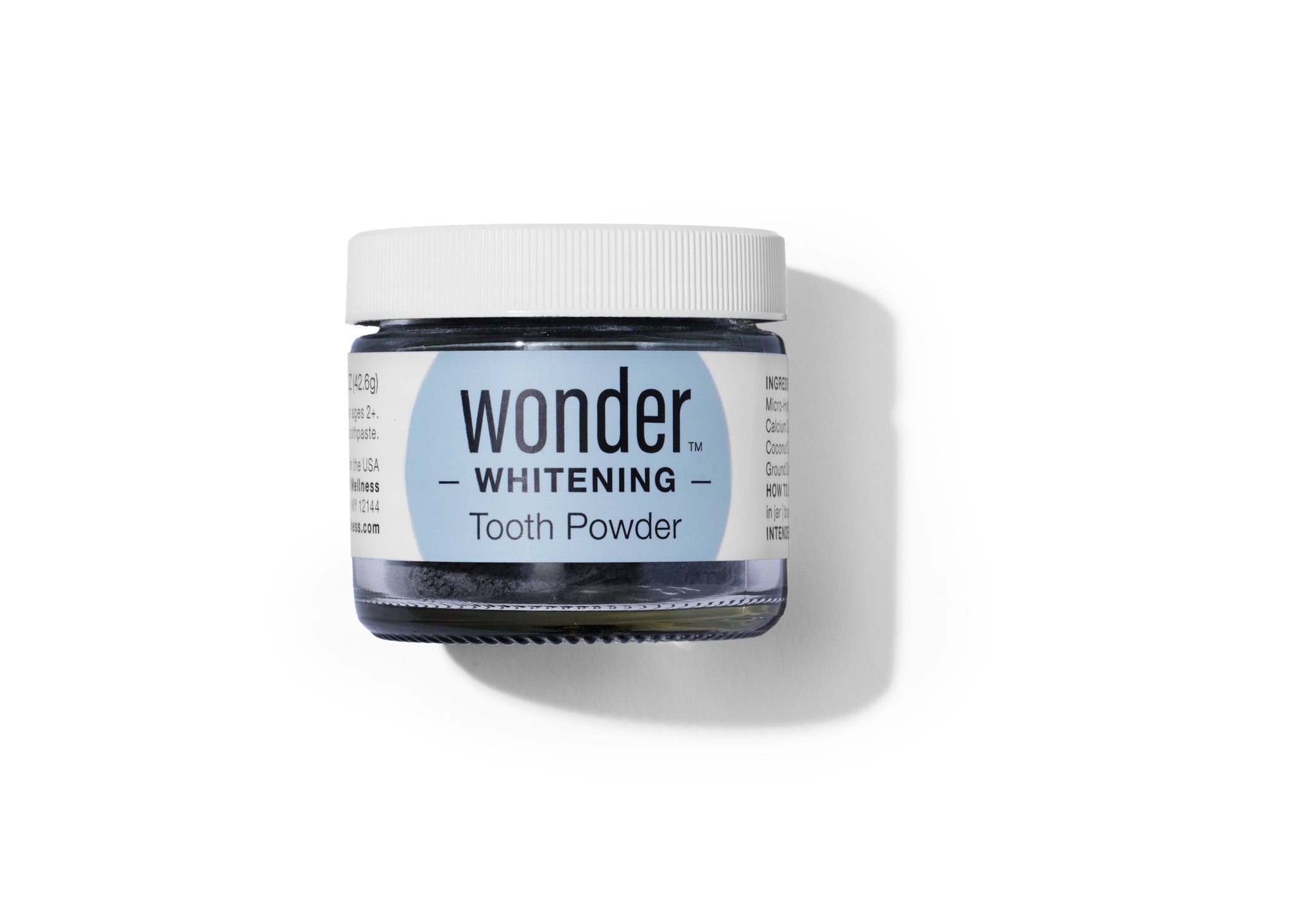 A jar of Wonder Whitening Tooth Powder sits on a white surface.
