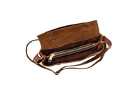 A brown leather crossbody bag displays its open interior with a zippered compartment.
