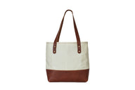Showcases a stylish Urban Southern tote bag featuring a cream canvas body and brown leather accents.

