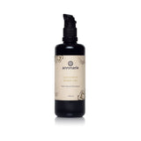 Annmarie's Coconut Body Oil, a herb-infused moisturizer in a dark bottle, sits on a white surface.

