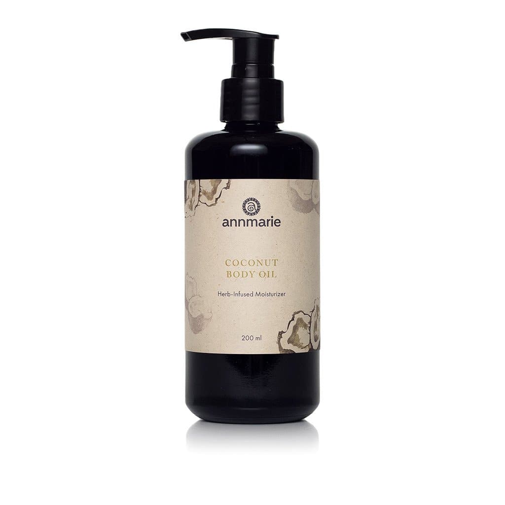 Annmarie Coconut Body Oil herb-infused moisturizer sits on a white surface.
