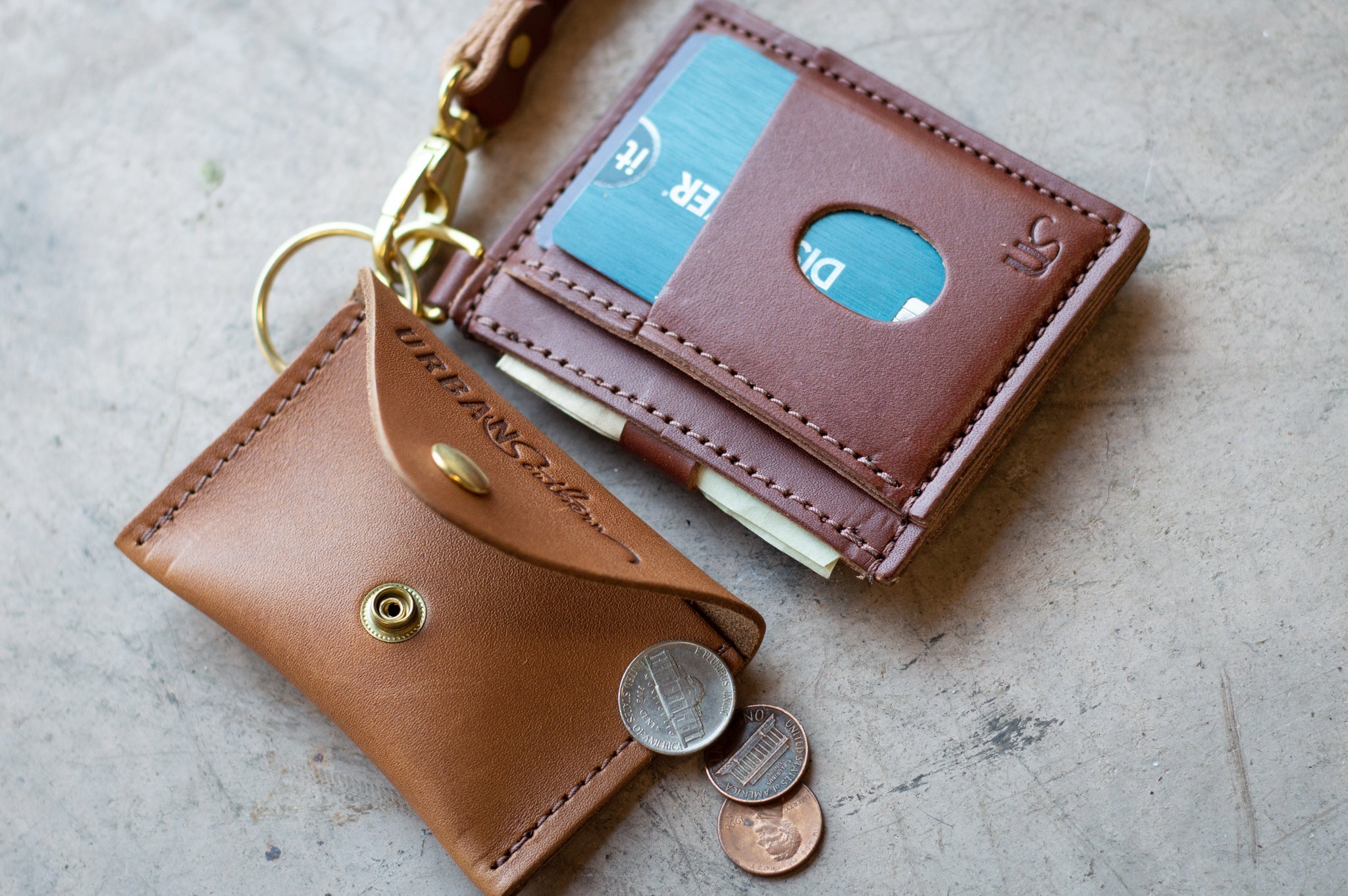 Leather wallet and coin purse set displays a credit card, cash, and loose change, showcasing everyday carry essentials.
