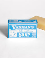 A bar of Vanman's Tallow & Honey Soap sits in its blue packaging next to a single unwrapped bar.
