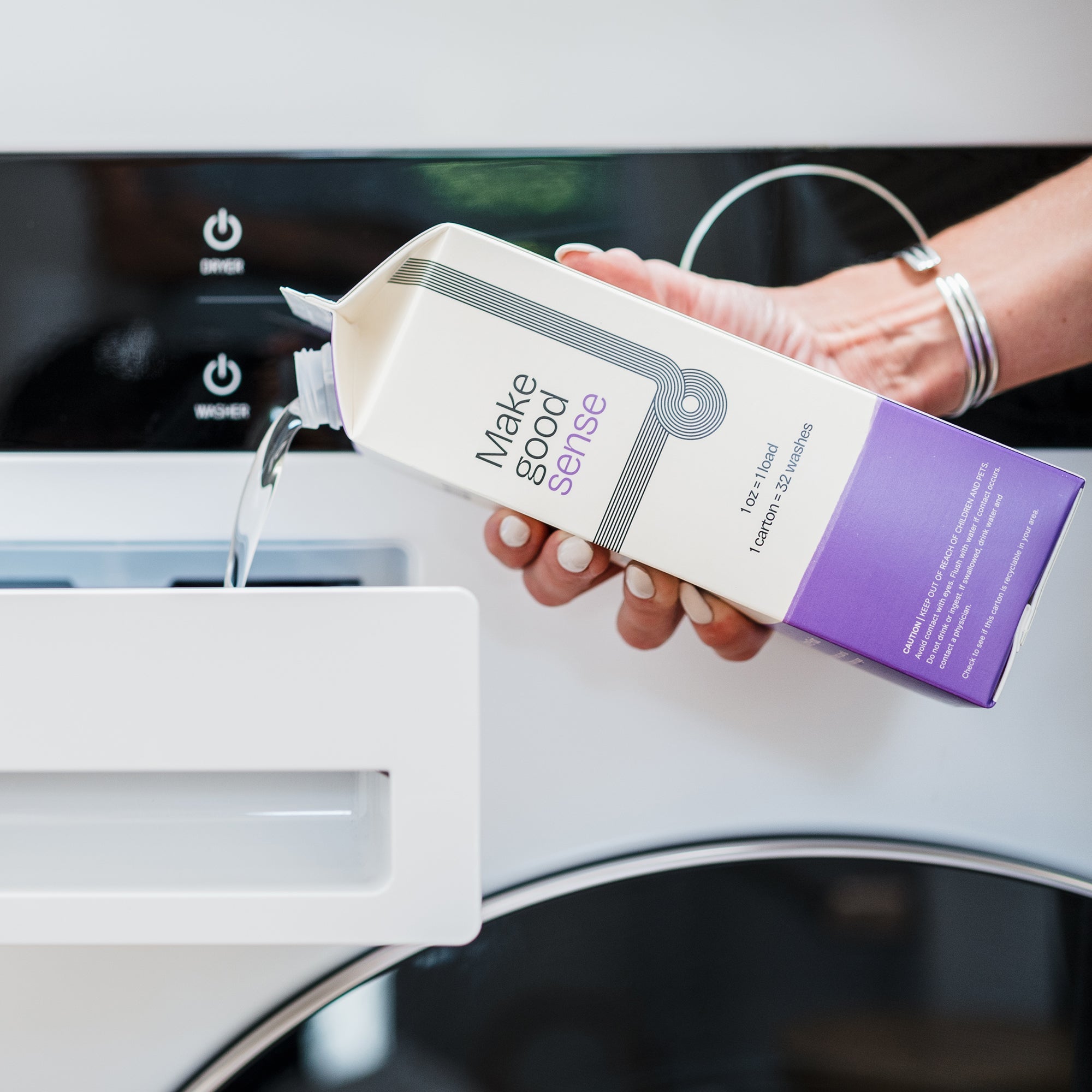 Woman pours eco-friendly "Make good sense" laundry detergent from a carton into a washing machine dispenser.