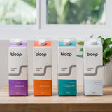 Four colorful Bloop brand laundry soap cartons stand in a row, displaying various scent options.
