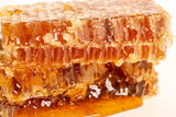 Close-up shows stacked pieces of natural honeycomb dripping with golden honey.
