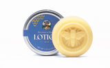 Beeswax lotion bar featuring a bee design sits beside its metal container from Register Family Bee Farm.
