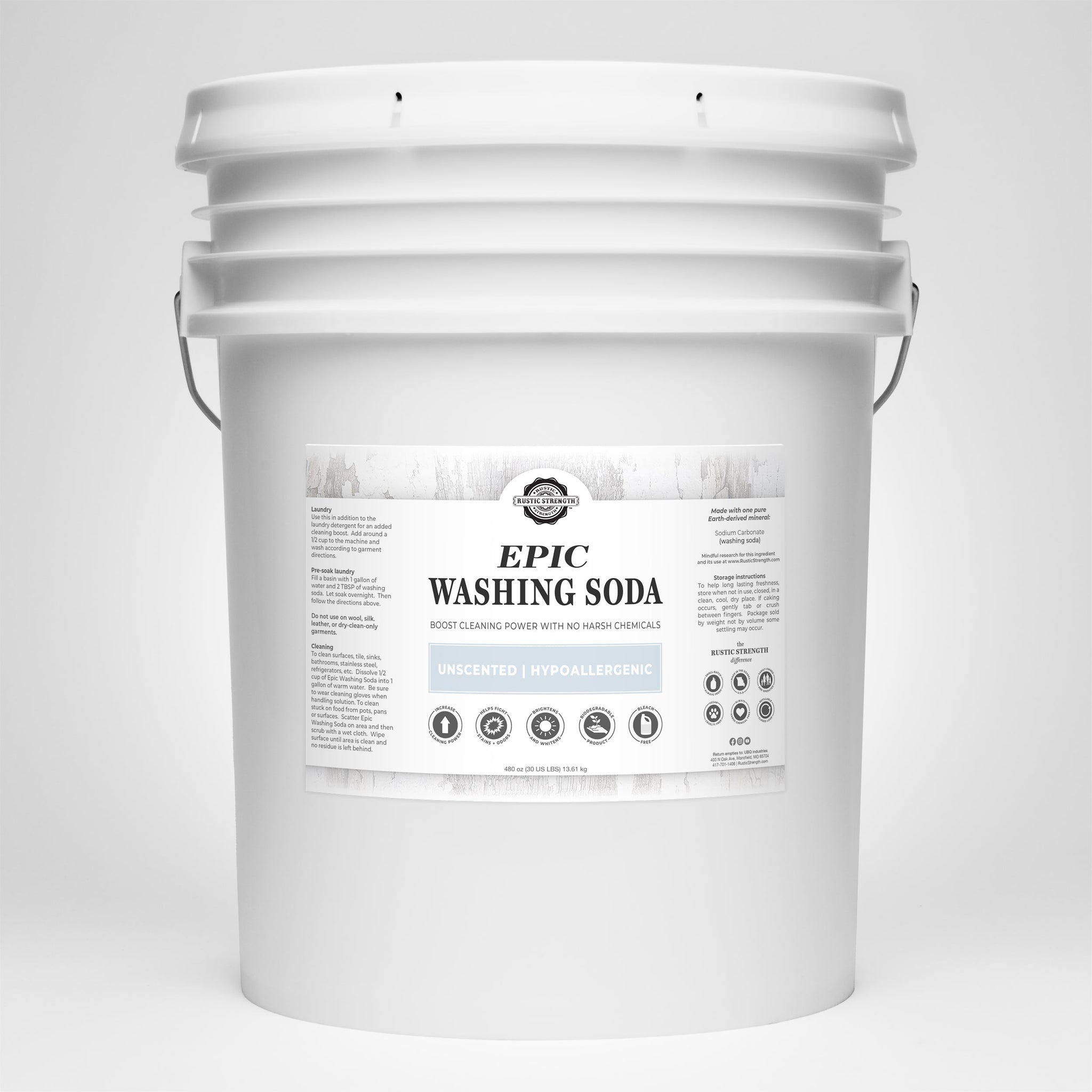 A large white bucket displays the label for Rustic Strength Epic Washing Soda, highlighting its unscented, hypoallergenic, and powerful stain-fighting qualities.
