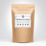 Showcases a brown paper bag containing Rustic Strength Epsom Salt Soak, a natural, unscented, hypoallergenic skin moisturizer.
