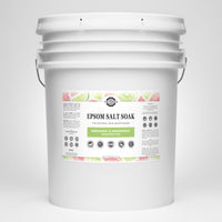 Examine a large white bucket filled with Rustic Strength Epsom Salt Soak, featuring bergamot and grapefruit essential oils for natural skin moisturizing.
