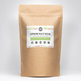 A kraft bag showcases Rustic Strength Epsom Salt Soak, a natural skin moisturizer with bergamot and grapefruit essential oils.

