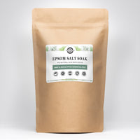 A kraft bag displays Rustic Strength Epsom Salt Soak with mint and eucalyptus essential oils, highlighting natural skin moisturizing benefits and biodegradable ingredients.