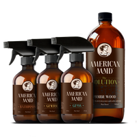 American Maid plant-based cleaning products, including bathroom cleaner, general cleaner, glass cleaner, and prairie wood scented solution, display elegantly against a black background.
