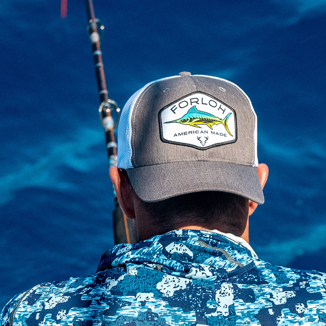 Person wearing a cap with 'Forloch' logo and fishing rod, against a blue water background